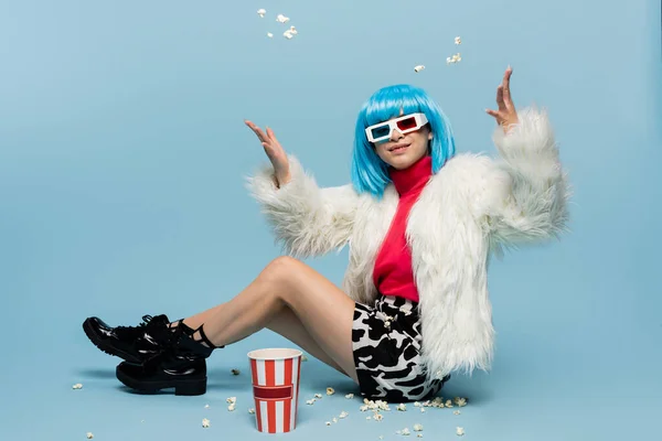 Lächelnde asiatische Pop-Art-Frau in 3D-Brille, die Popcorn auf blauem Hintergrund wirft — Stockfoto