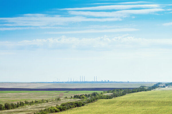 Landscape with agricultural land and industrial facilities on the horizon