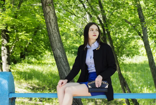 미니 스커트는 도시 공원에 있는 벤치에 앉아 있는 여자 — 스톡 사진