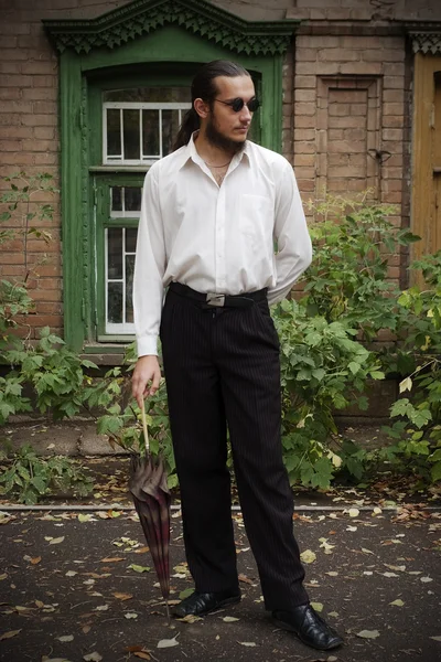 Ung man med ett paraply promenader genom staden — Stockfoto