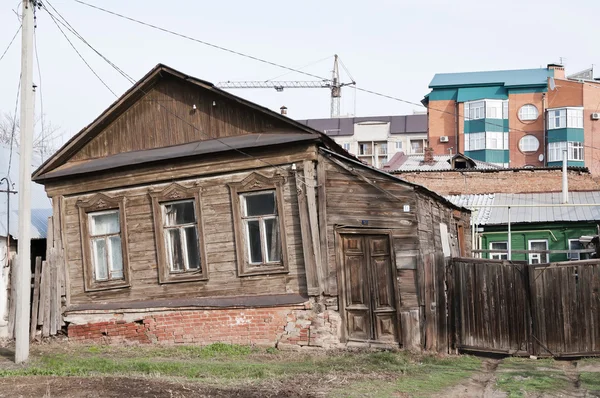 Старый шаткий дом на фоне новых зданий — стоковое фото