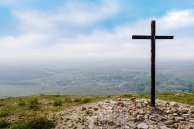 Mahvolmuş bir kilisenin yerinde bir haç. Bir köy ile kırsal bir manzaranın üst görüntüsü. Fotoğraf, Rusya 'nın Orenburg bölgesindeki Andreevka köyü yakınlarındaki Chasovnaya dağının tepesinde çekildi.