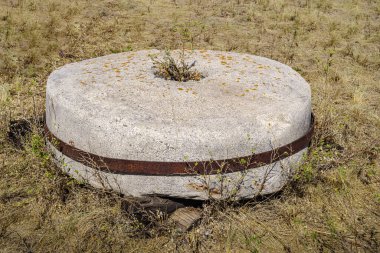 Yel değirmeninin çimlerin üzerinde duran eski bir değirmen taşı.