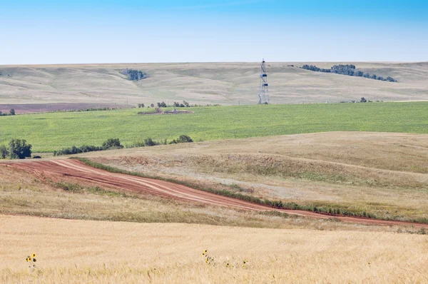 Rural landscape with a drilling derrick — Stock Photo, Image
