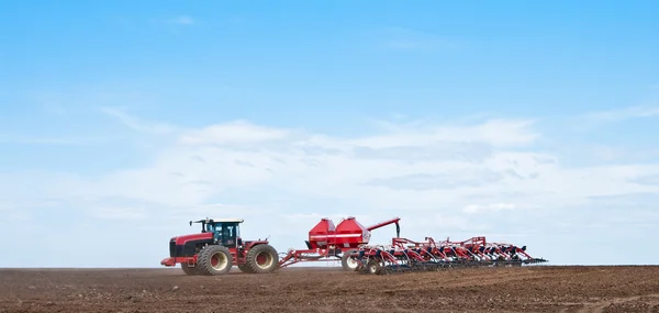 Traktor med såmaskin ute på fältet — Stockfoto