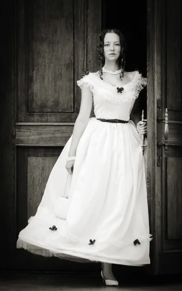 Girl in a vintage dress coming out of doors — Stock Photo, Image