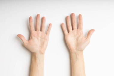 A pair of hands placed on a white surface with palms facing upward and fingers spread open. The lighting is soft and even, highlighting the natural lines and texture of the palms. The composition 