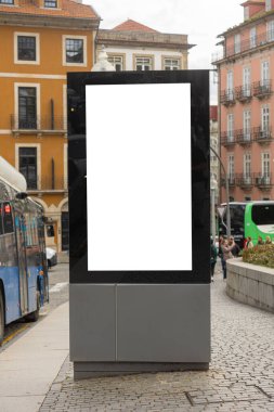 Porto, Portekiz 'de yağmurlu bir caddedeki otobüs durağında boş reklam panosu ıslak kaldırımlar, park edilmiş arabalar ve arka planda şemsiyelerle yürüyen insanlar..