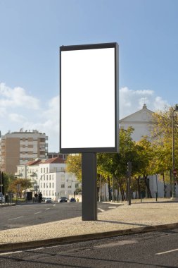 Sakin bir şehir caddesindeki boş bir reklam panosunun gündüz görüntüsü, klasik sarı bir bina ve açık mavi bir gökyüzü..