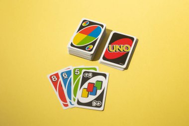 Lizbon, Portekiz - 2025-11-13 UNO kart oyunu sarı arka planda desteleri ve popüler aile oyunundan yayılmış kartları gösteriyor. Parlak ve eğlenceli kompozisyon, eğlence ve eğlence..