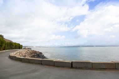 Portekiz 'in Oeiras kentindeki sahil şeridi boyunca sakin deniz, kayalar ve bulutlu gökyüzü seyahat ve doğa arka planı için mükemmel..