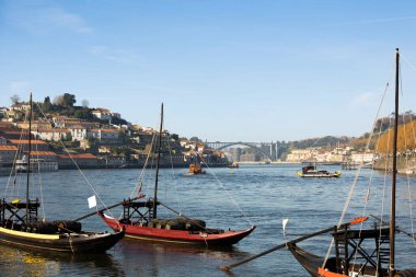 Portekiz 'in Porto kentindeki Douro Nehri manzarasında ön planda geleneksel haham tekneleri yer alıyor. Suyun karşısında, Vila Nova de Gaia 'nın yamacı tipik Portekiz evlerini gösteriyor.