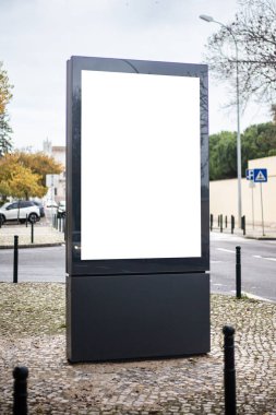 Boş beyaz ekranlı büyük dikey reklam panosu şehir dışındaki bir kaldırımda kaldırımda duruyor. Lizbon 'da