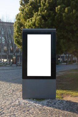 Lizbon, Portekiz 'deki bir şehir parkında beyaz fotokopi alanı olan boş bir reklam panosu. Modern şehir sokak mobilyaları ağaçlar ve kaldırımlarla çevrili, modeller, marka ve reklam kavramları için ideal..
