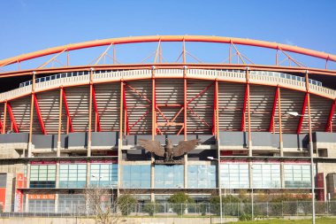 Lizbon, Portekiz 'de güneşli bir günde Lizbon, Portekiz' de açık bir gökyüzü altında kırmızı çelik yapısı ve oturma yerleriyle büyük ve modern bir futbol stadyumunun dış görüntüsü çekildi..