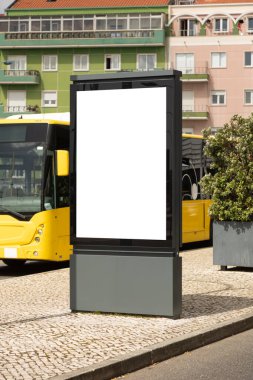 Şehir merkezindeki bir otobüs durağında, arkasında sarı bir şehir otobüsü ve konut binaları olan boş bir tabela modeli. Toplu taşıma ortamında pazarlama kampanyaları için fotokopi alanı olan temiz reklam görüntüsü.