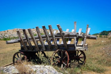 Açık mavi gökyüzü olan eski ahşap bir at arabası.