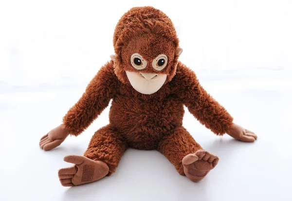 Beyaz arka planda oturan oyuncak maymun.