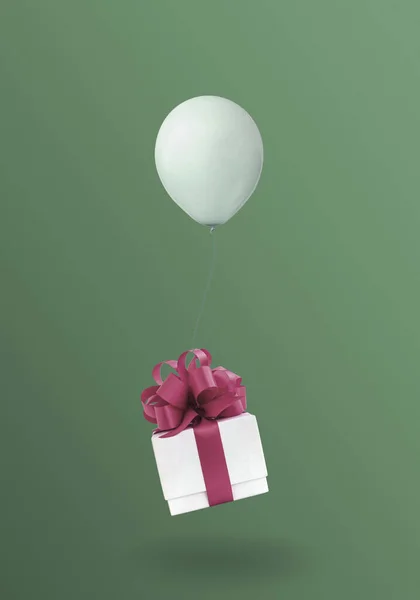 Kırmızı kurdeleli beyaz hediye kutusu yeşil arka planda