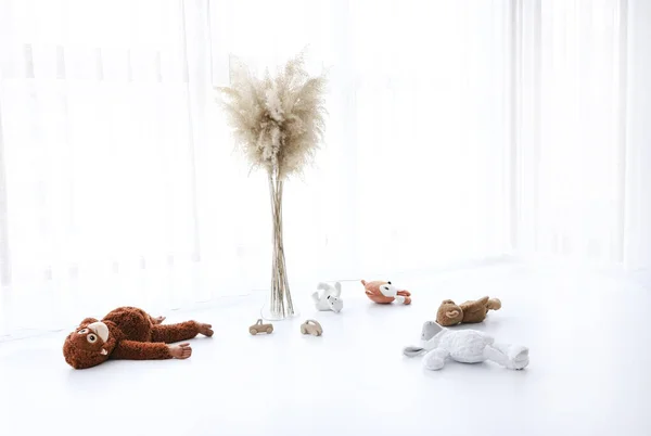 Beyaz zemin üzerinde bebek odası ayı, maymun, tilki, ahşap araba oyuncakları.