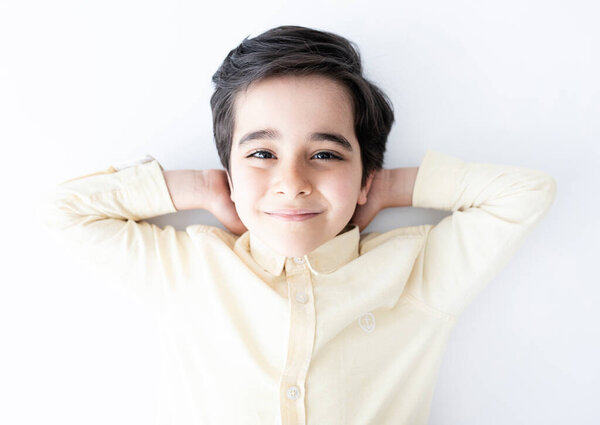 Счастливый и милый маленький мальчик лежит на земле.