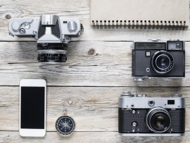 Cep telefonu, pusula ve ahşap masa üzerinde vintage kameralar.