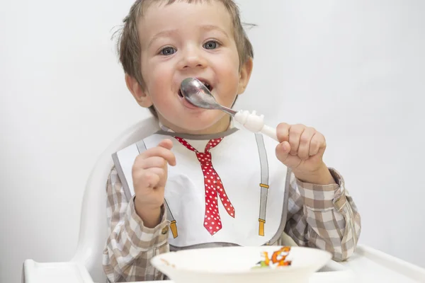 Little boy is eating using spoon — Stock Photo, Image