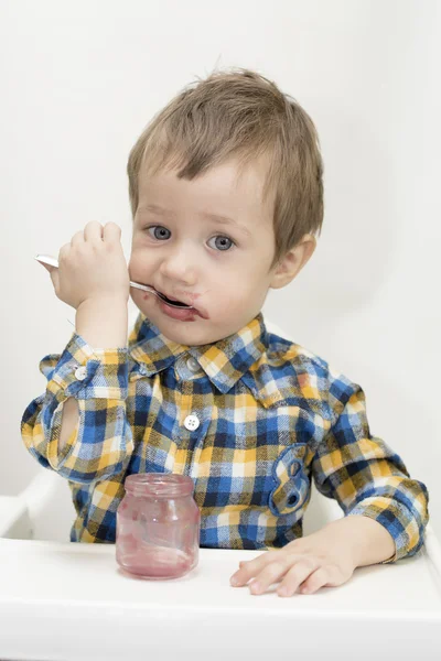 Little boy is eating using spoon — Stock Photo, Image