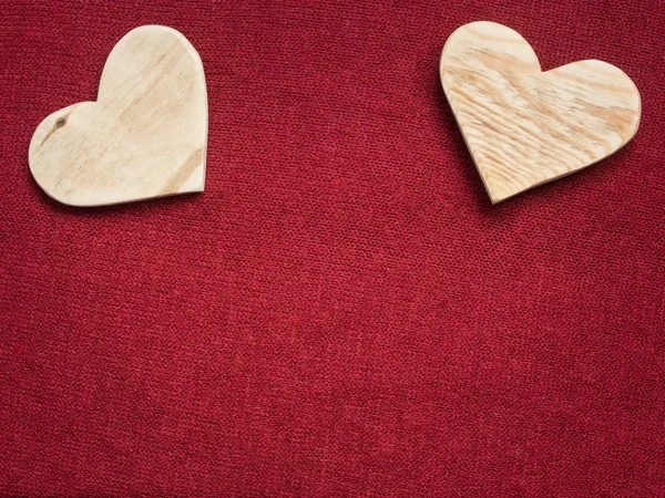 Dos corazones de madera sobre un fondo de tela roja — Foto de Stock