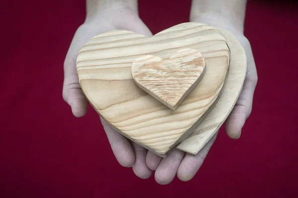 Mujer con un montón de corazones de madera en sus palmas — Foto de Stock