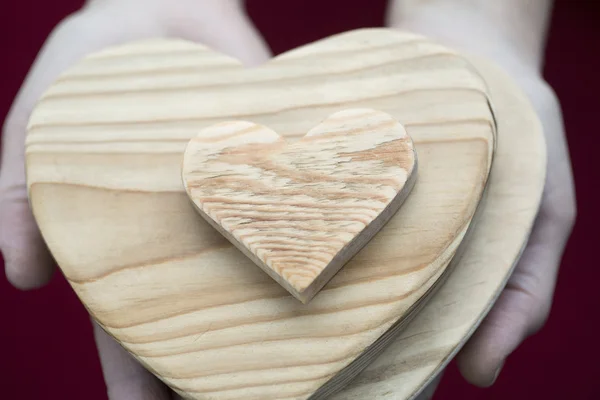 Mujer sosteniendo en palmas pila de corazones de madera — Foto de Stock