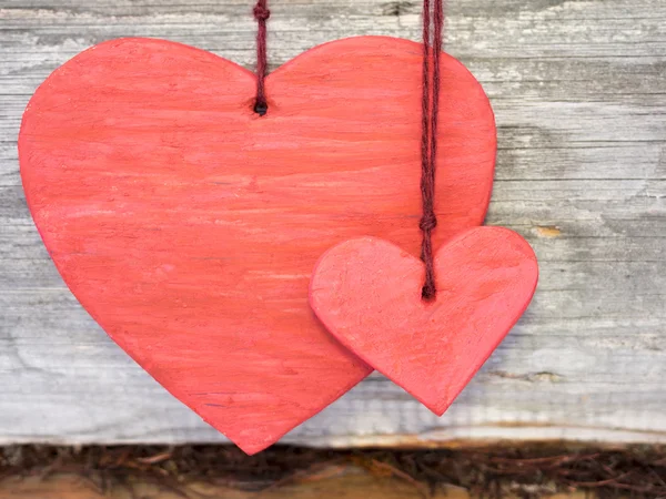 Dos colgante corazón rojo sobre un fondo de madera . — Foto de Stock
