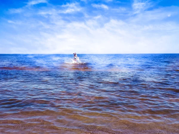 Beautiful girl between shining water of blue sea