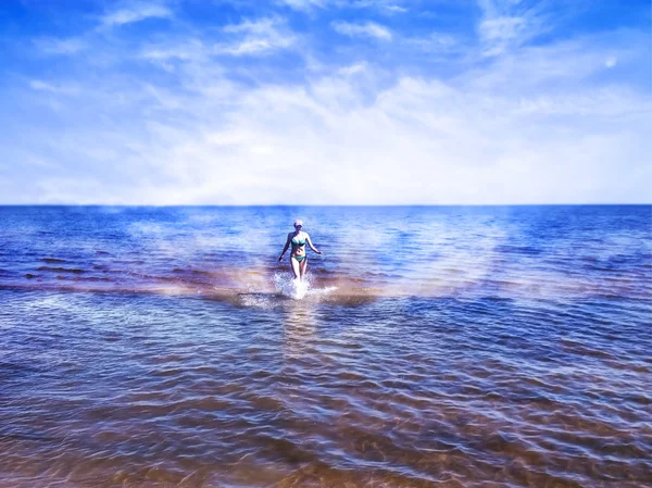 Menina bonita indo entre a água brilhante do mar azul — Fotografia de Stock