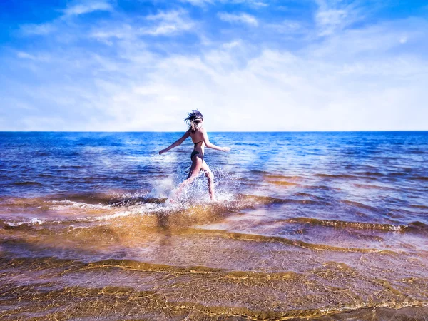 Hermosa joven corriendo en salpicaduras de brillante transparente — Foto de Stock