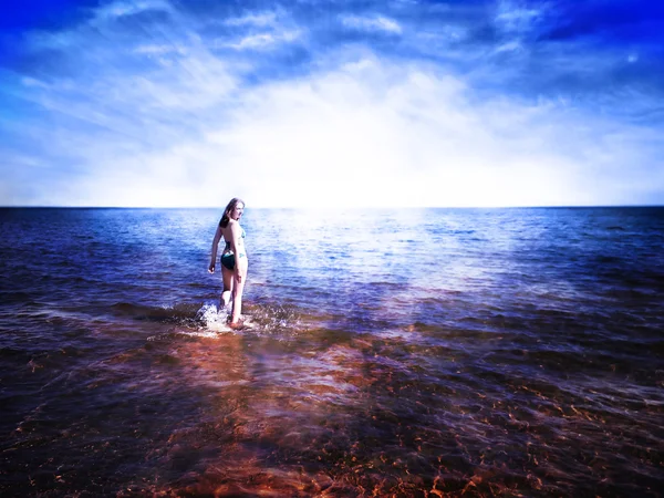 輝く上昇 su に向かって水の上を歩く美しい若い女性 — ストック写真