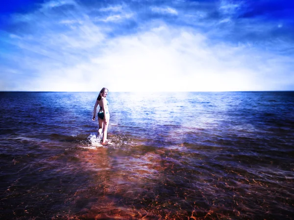 Hermosa joven mujer caminando sobre el agua brillante hacia el aumento de su Imagen de stock