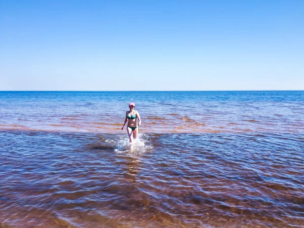 Belle jeune femme courant sur de l'eau transparente — Photo