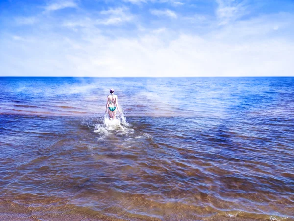 Bella ragazza che cammina sull'acqua splendente del mare blu — Foto Stock