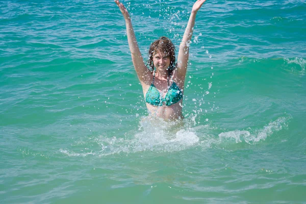 Mooie jonge vrouw in spray van de zee — Stockfoto