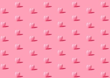Pembe tüylerle kaplı küçük kalplerden oluşan bir desen. Pastel pembe arka planda 45 derece açı.