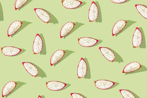 Pattern created from fresh exotic dragon fruit slices on pastel green background. Top view.