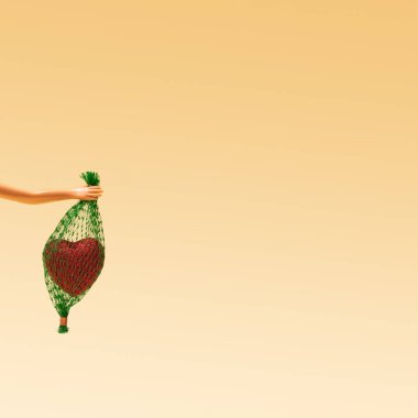 İçinde kalp olan küçük bir çanta taşıyan kadın el düzenlemesi. Romantik bej arkaplan.