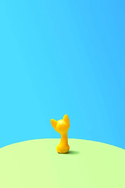 Single yellow cat toy seats on green and blue background.