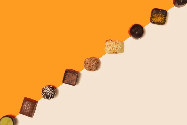 Deliciosas Coloridas Trufas Chocolate Pralinés Alineados Diagonal Contra Naranja Brillante — Foto de Stock