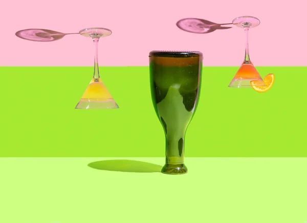超現実的な魔法のパーティーの概念 上下逆さまの方向に2つのフル上下カクテルグラスとその上に立ってボトル ライトグリーン ピスタチオグリーン ピンクの背景 — ストック写真
