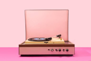 60 'lardan kalma gramofon plakçısı. Pembe popolu ve açık pembe arka planlı tek vinil için döner tablo.