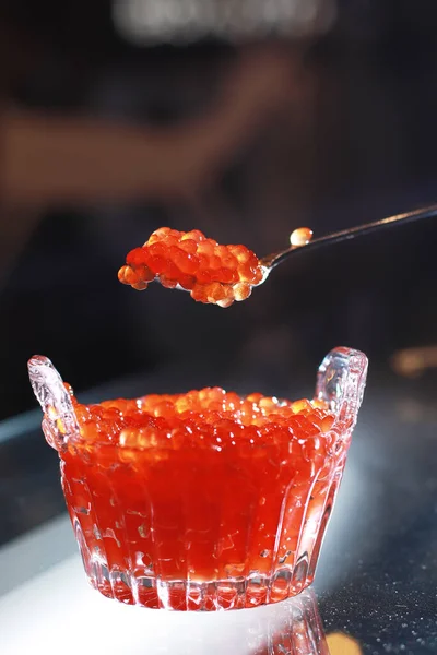 厨师把一汤匙发亮的红色鱼子酱放在一碗红色鱼子酱的侧面 — 图库照片