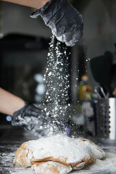 手袋をはめた手で調理し、生地をこね、テーブルサイドビューに小麦粉を振りかける ロイヤリティフリーのストック画像