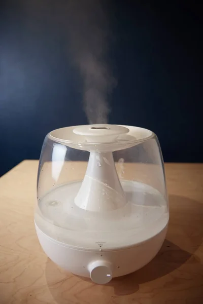 a white steam generator on the table stands running emits steam close up view from the side